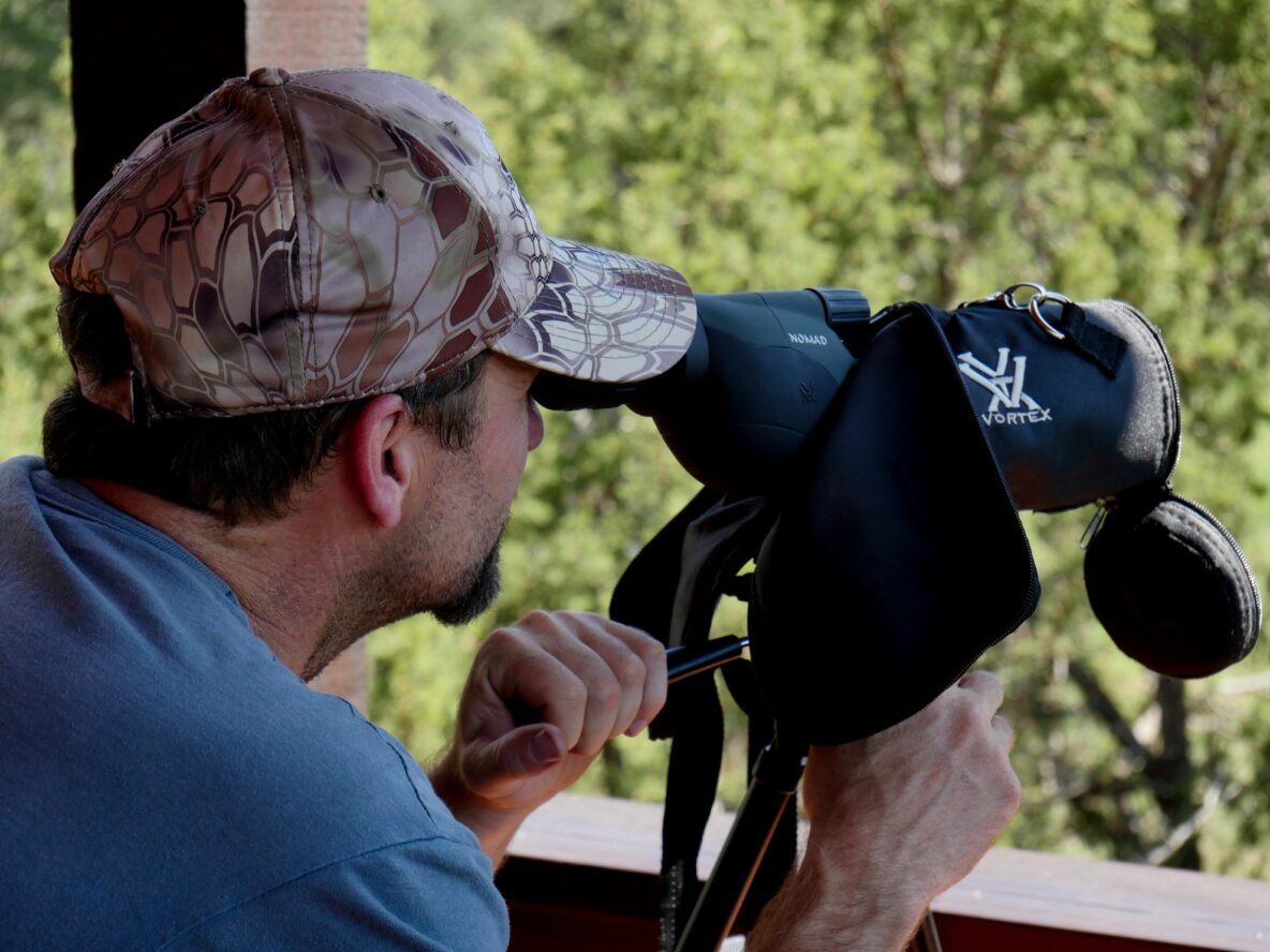 Image of a spotter looking down range through a scope