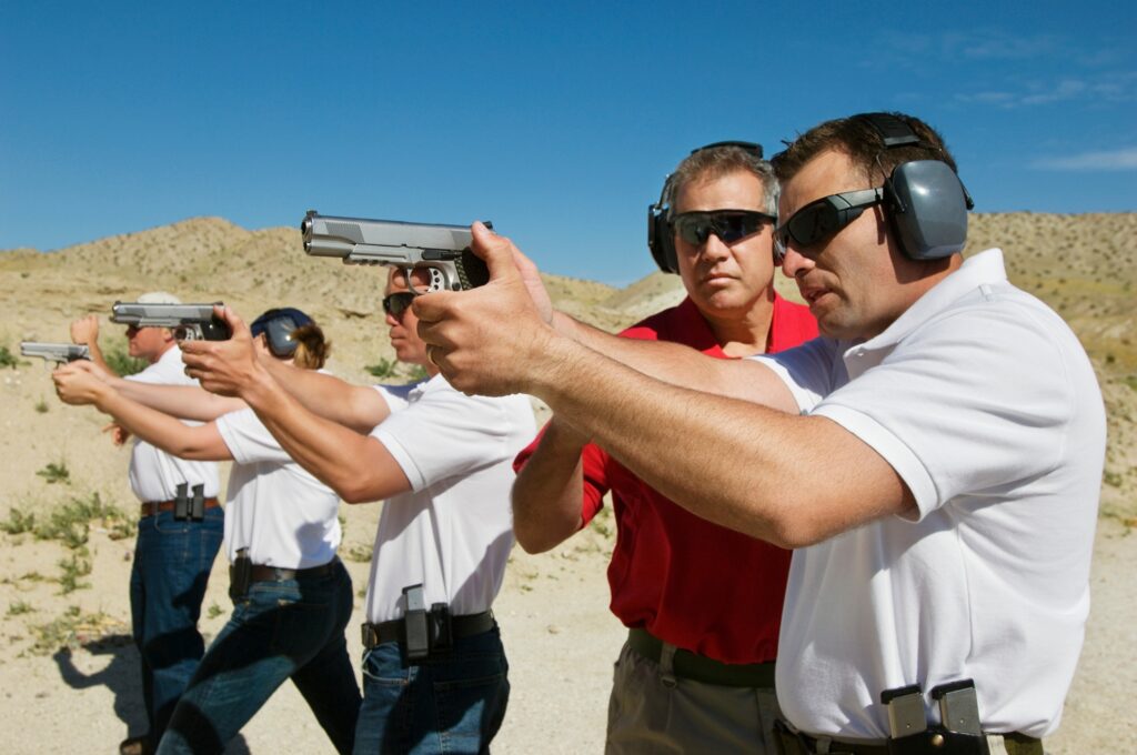 Instructor assisting officers with hand guns at firing range during weapons training